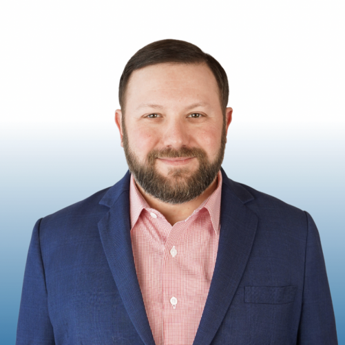 Bearded man in a blue blazer and pink shirt, Equity team member headshot